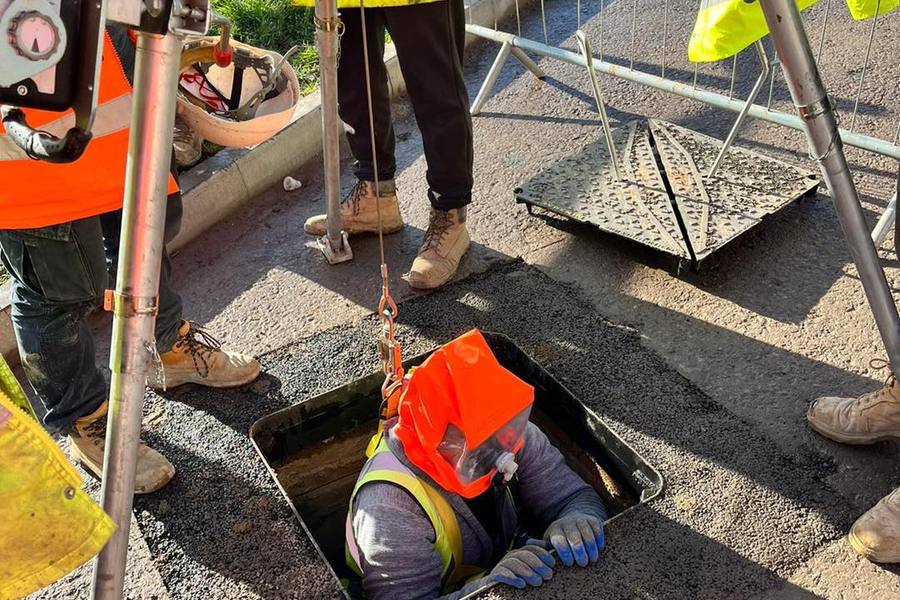 Operative entering a confined space with tripod and rescue equipment