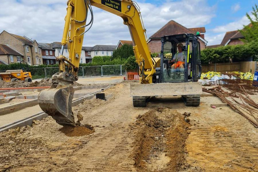 Excavator digging a service trench on a housing development